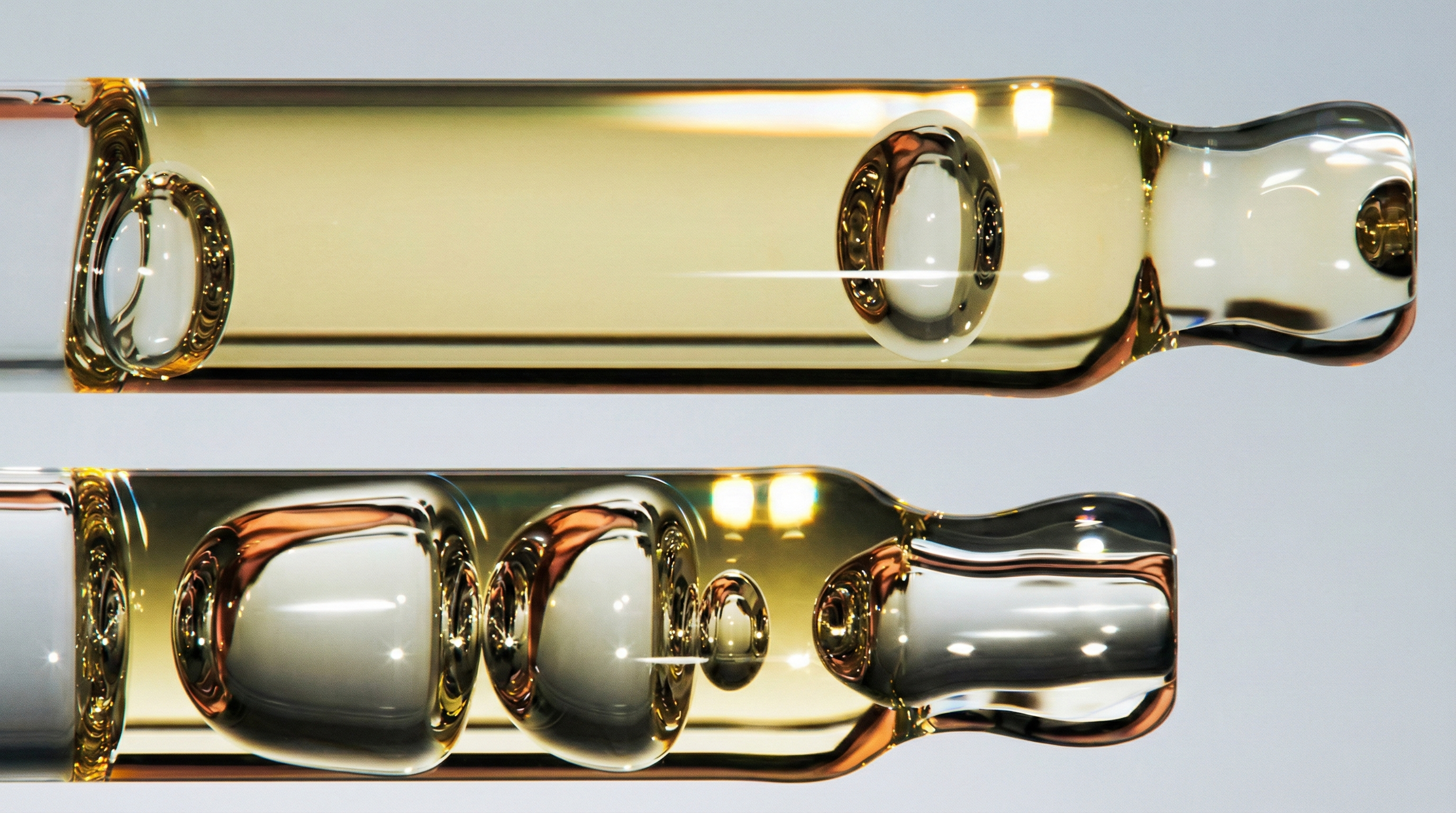 Close-up of facial serums in glass vials showcasing golden and clear liquid textures in a skincare collection.