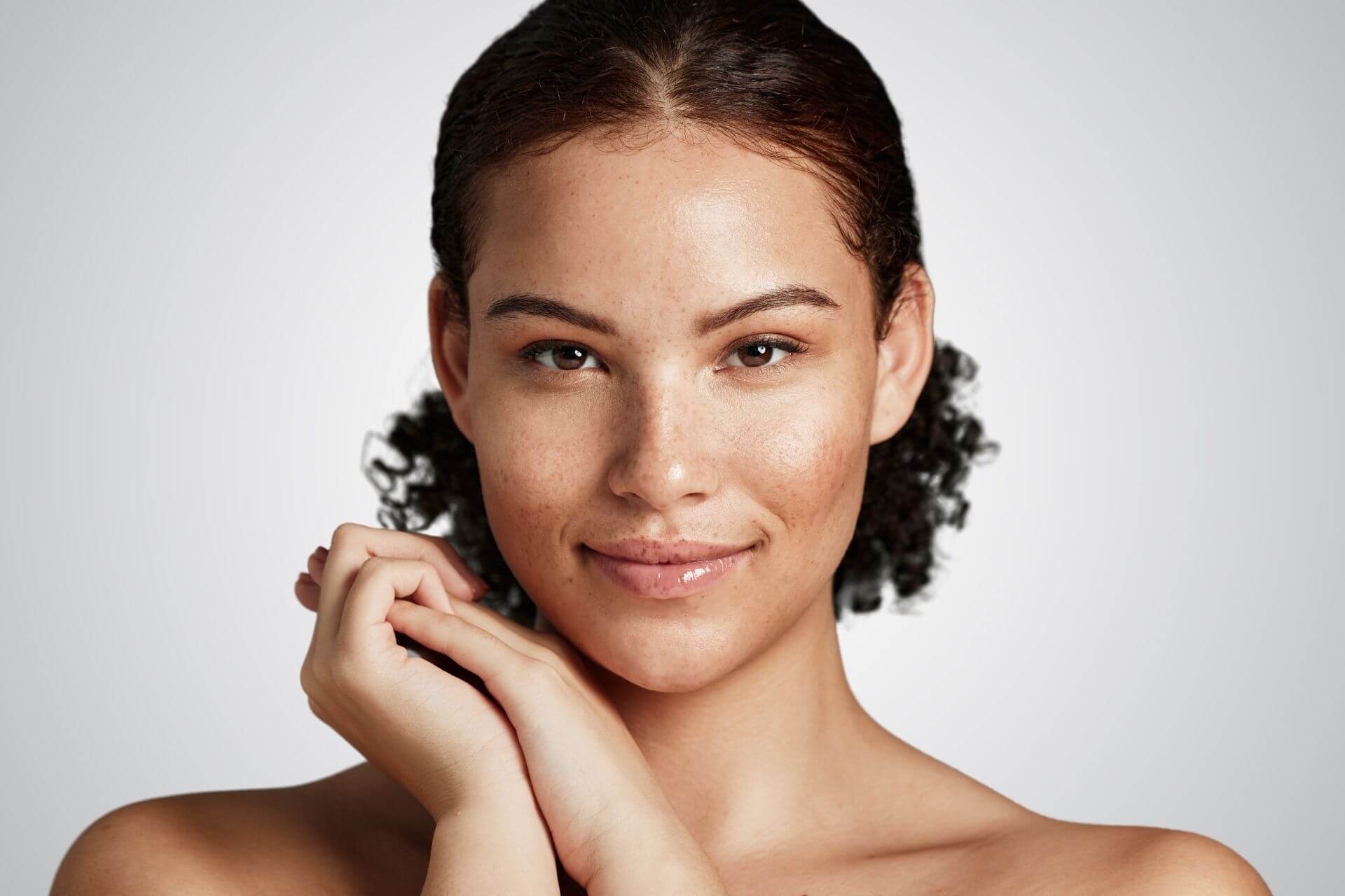 Smiling woman with glowing skin, representing a healthy oily skin complexion. A balance of hydration and oil control is essential for skincare. Featured on Allana Davis Studio.